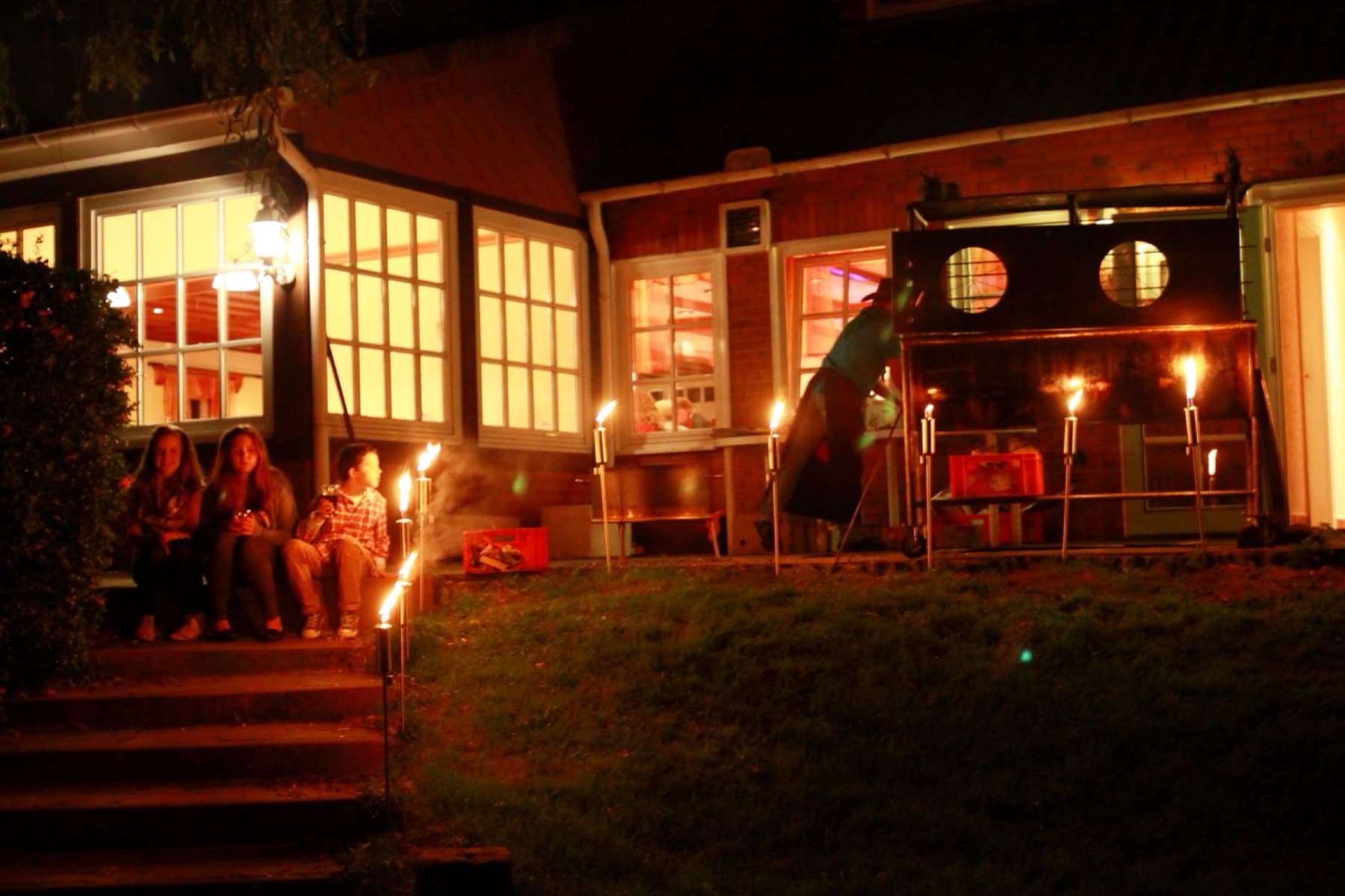 Gartenfest am Abend mit Fackeln und beleuchtetem Haus