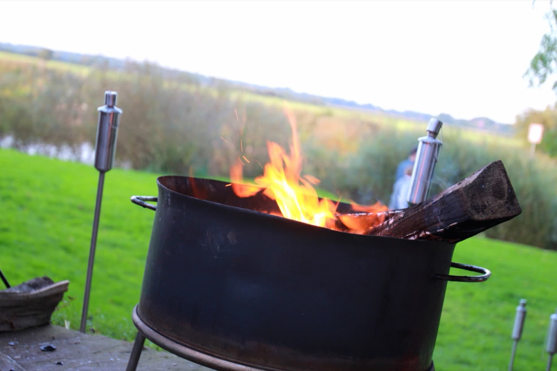 Feuerkorb mit Flammen am Wasser