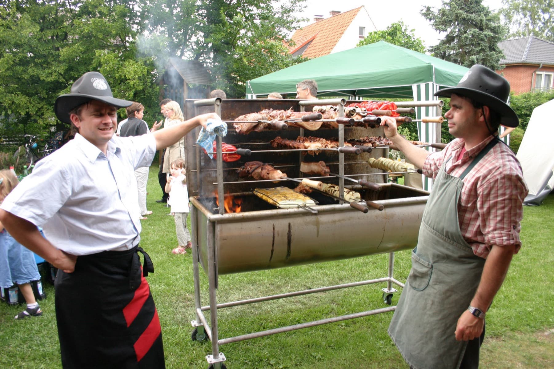 Zwei Grillmeister am Spießgrill auf einem Gartenfest